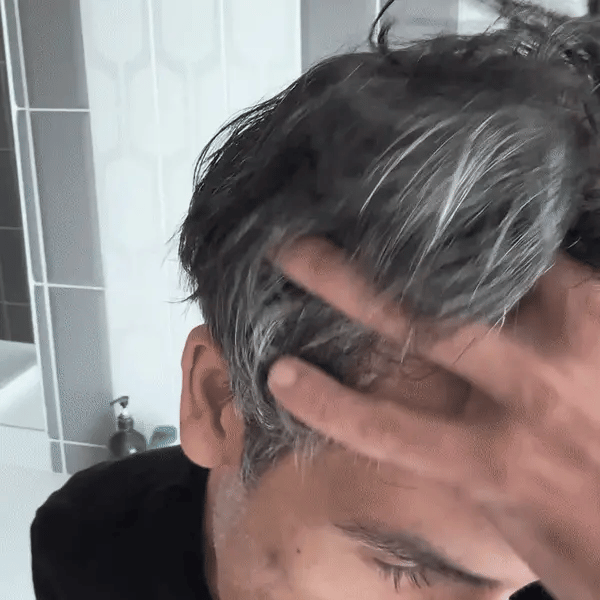 Woman lifting her hair to show gray roots along her part